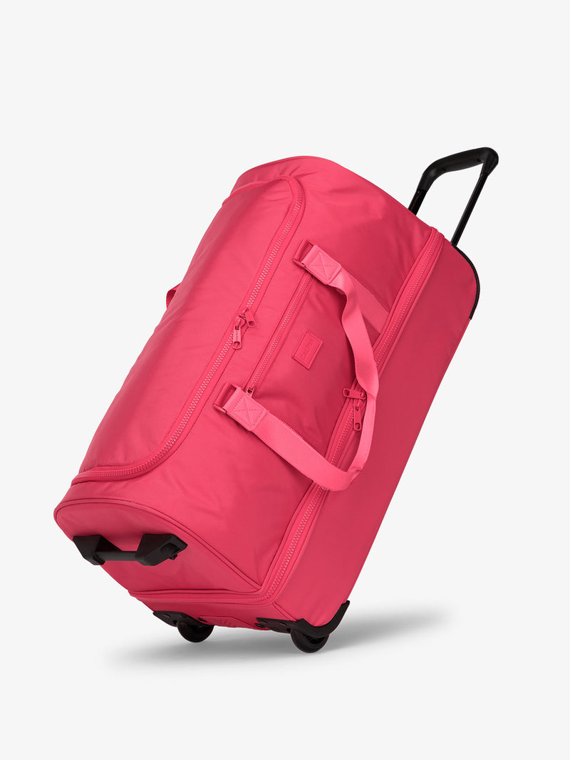 Side view of CALPAK Stevyn Large Rolling Duffel in dragonfruit pink