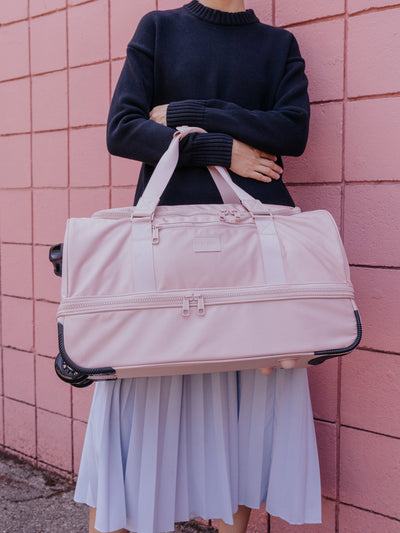 CALPAK Stevyn Rolling Duffel side view with top handle extended in pink sand; DSR2201-PINK-SAND view 2
