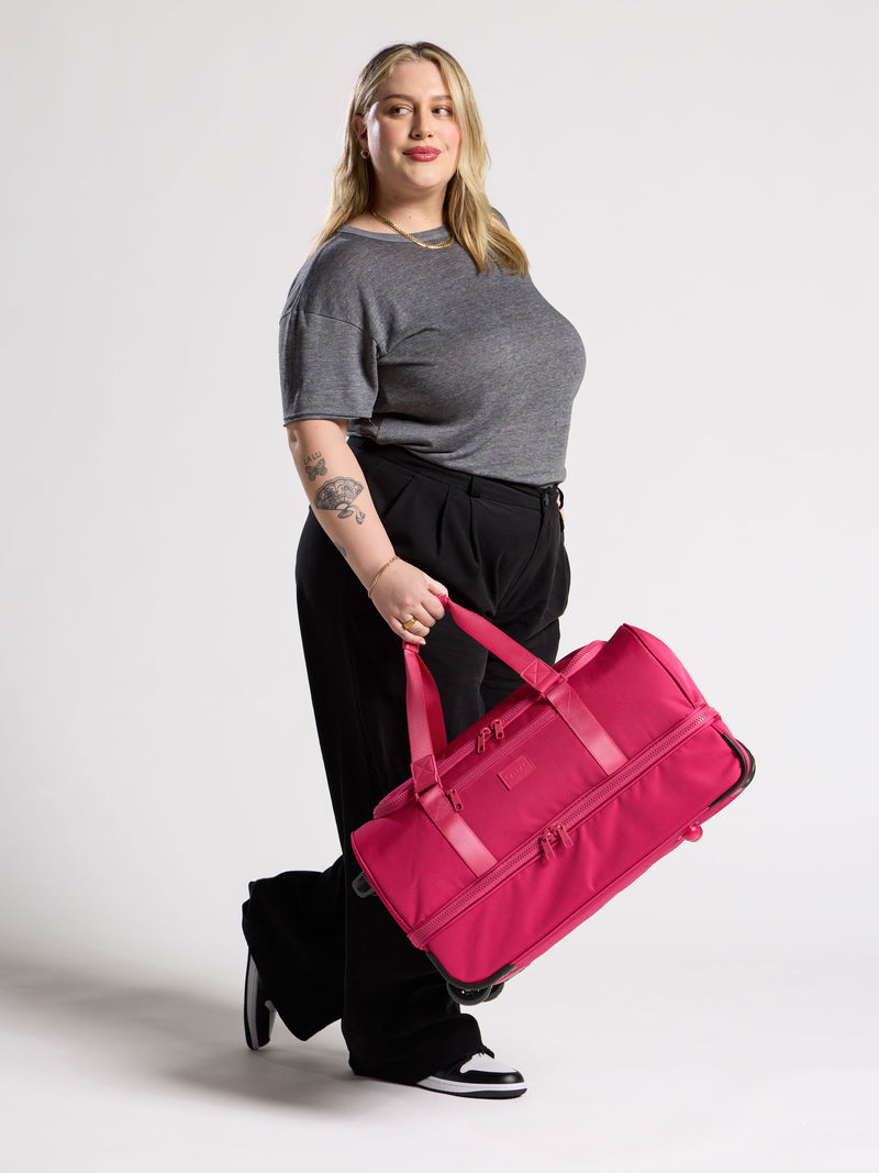 Hot pink CALPAK Stevyn Rolling Duffel featuring dual handles