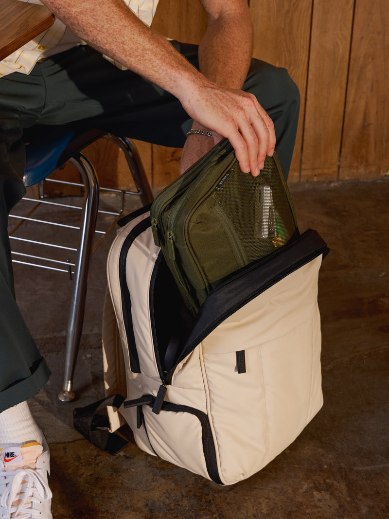 Model placing CALPAK Tablet Tech Organizer in moss inside Luka Laptop Backpack in oatmeal