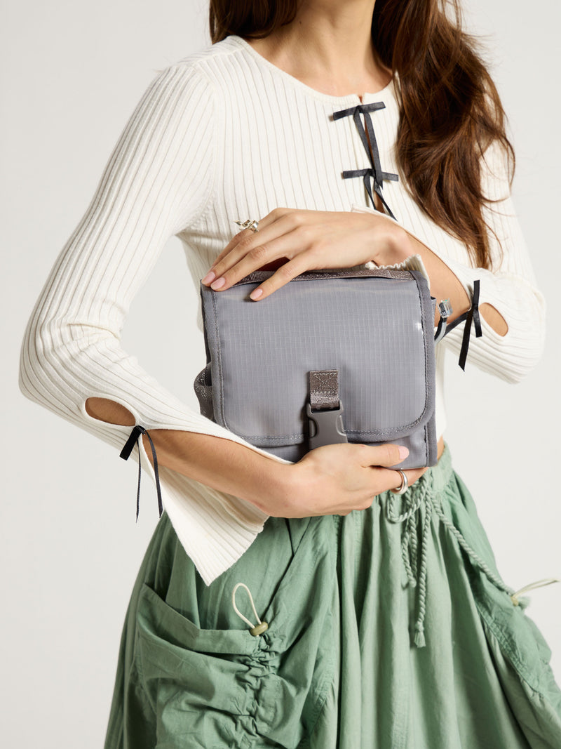 Model holding CALPAK Terra Hanging Toiletry Bag in gray storm