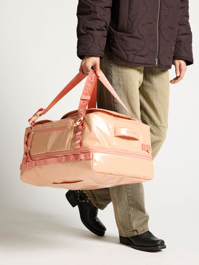 Model holding CALPAK terra large 50L duffel backpack as duffel bag in orange canyon