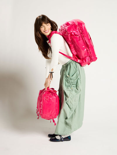 Model wearing CALPAK Terra Large 50L Duffel Backpack on back with Terra 26L Laptop Duffel Backpack in hands in dragonfruit