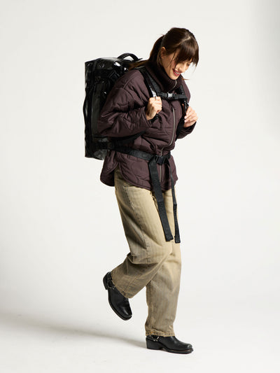 Model wearing CALPAK terra large 50L duffel backpack and displaying adjustable top chest strap and bottom waist strap