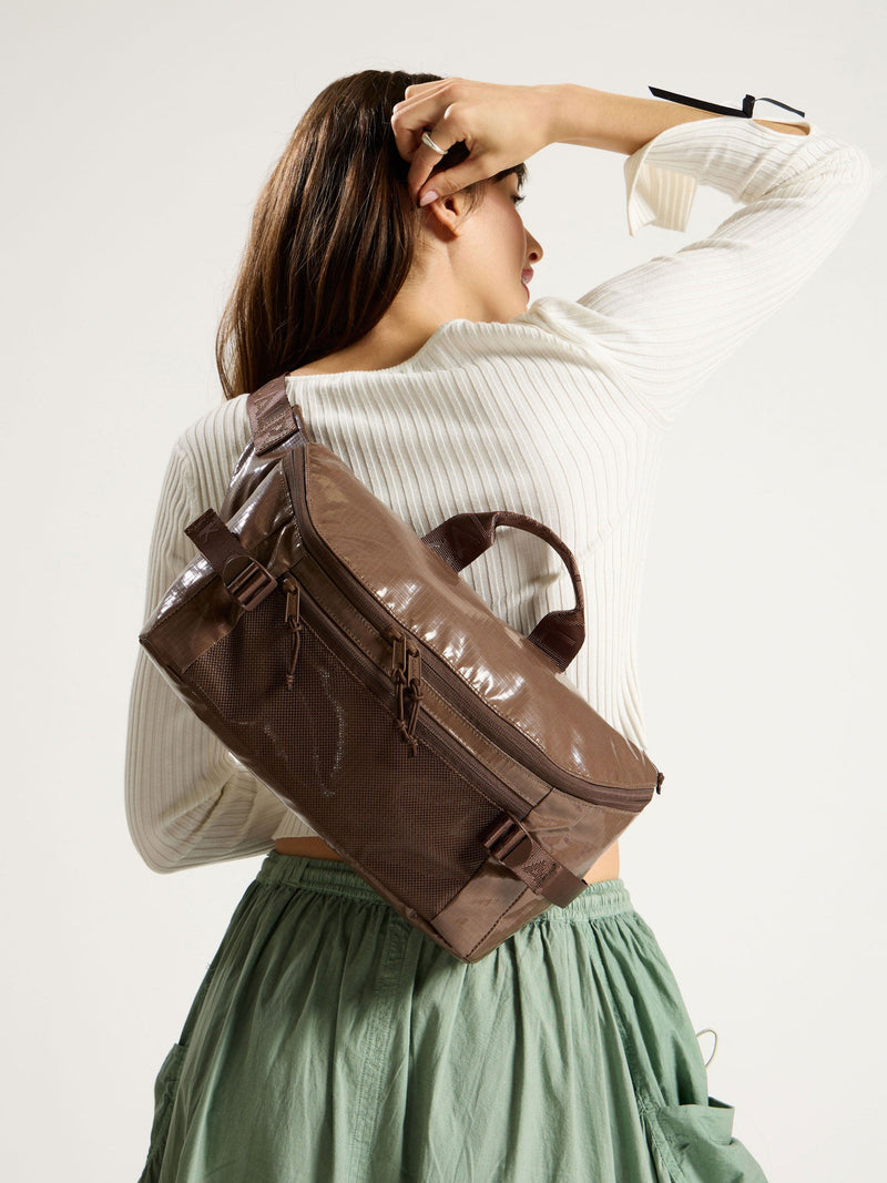 Model wearing CALPAK Terra Sling Bag in chocolate as crossbody bag