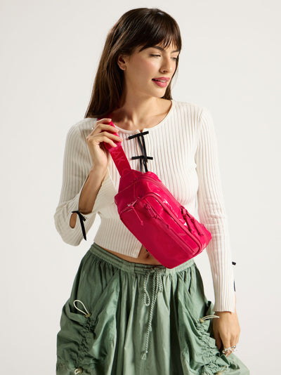 Model wearing CALPAK Terra Small Sling Bag in pink dragonfruit as crossbody bag