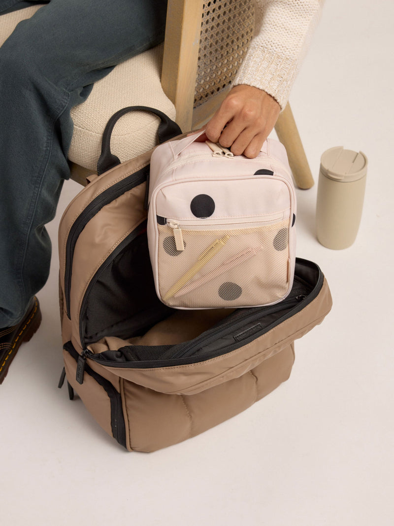 Model placing passport inside front mesh pocket of polka dot CALPAK The Everything Cube