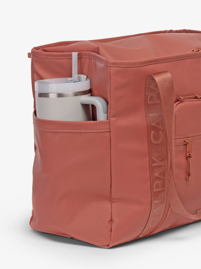 CALPAK Terra 35L Water Resistant Zippered Tote Bag in red and orange Matte Clay side pocket used as as water bottle holder