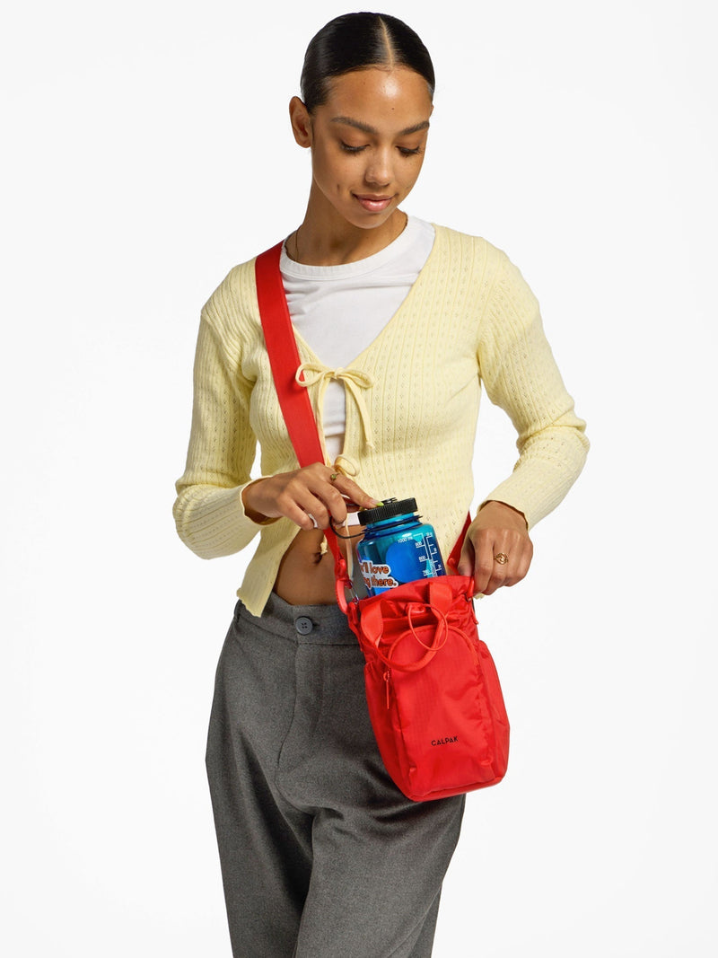 Model placing water bottle inside CALPAK Water Bottle Holder in rouge