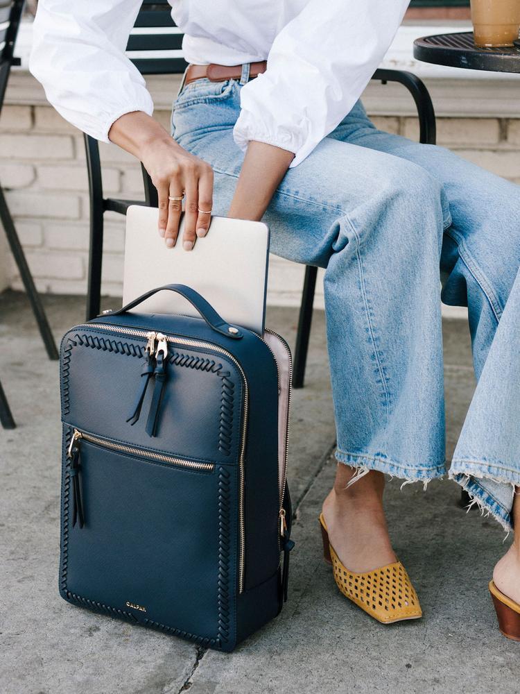 model packing a computer to navy blue CALPAK Kaya laptop backpack