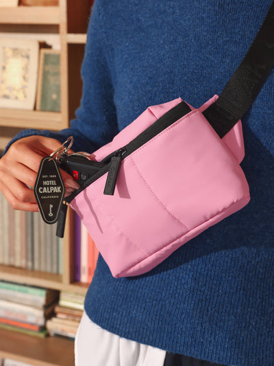 Model wearing CALPAK Luka small fanny pack as a crossbody belt bag in pink