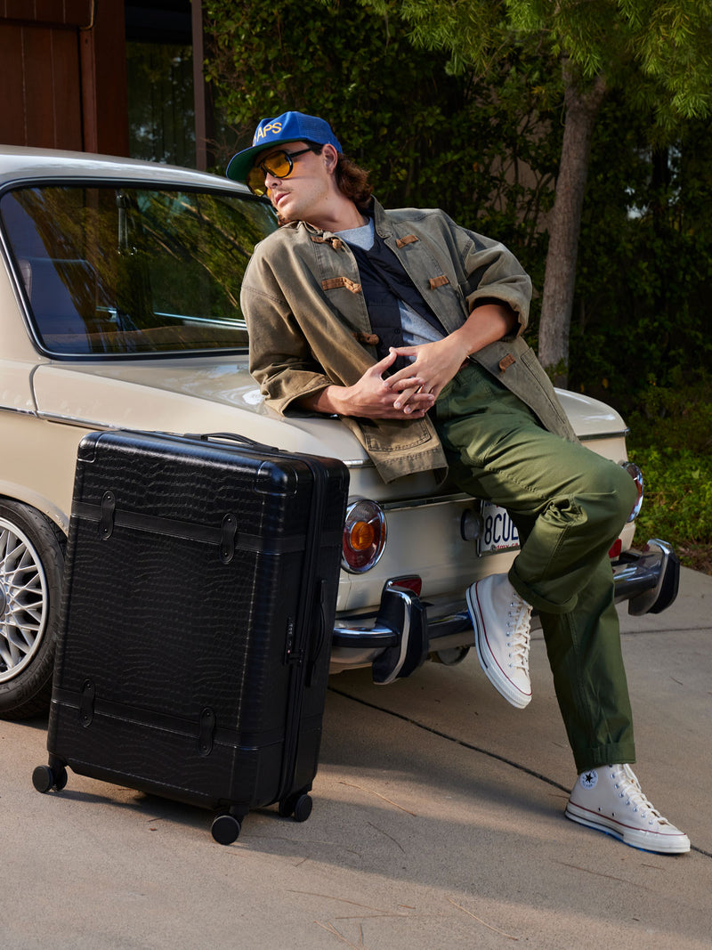 male model with CALPAK TRNK beige almond luggage set in vintage trunk style