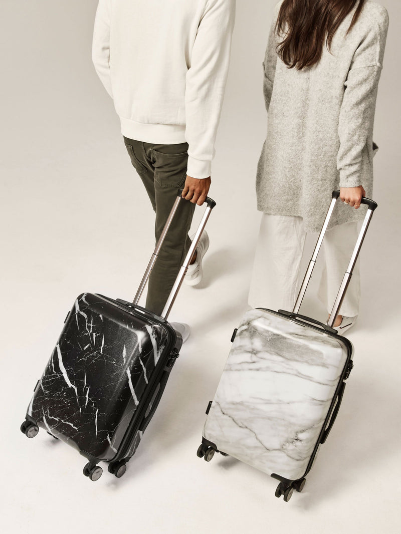 couple rolling CALPAK Astyll black and white hardside marble carry on suitcases